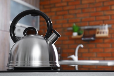 Modern kettle with whistle on stove in kitchen, space for text