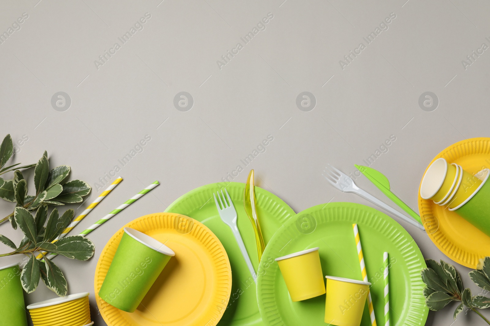Photo of Flat lay composition with disposable tableware on light grey background. Space for text