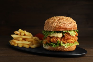 Delicious burger with crispy chicken patty and french fries on wooden table