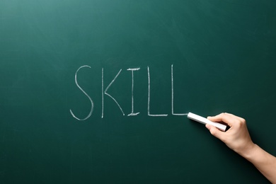 Photo of Woman writing word SKILL on chalkboard. Business trainer concept