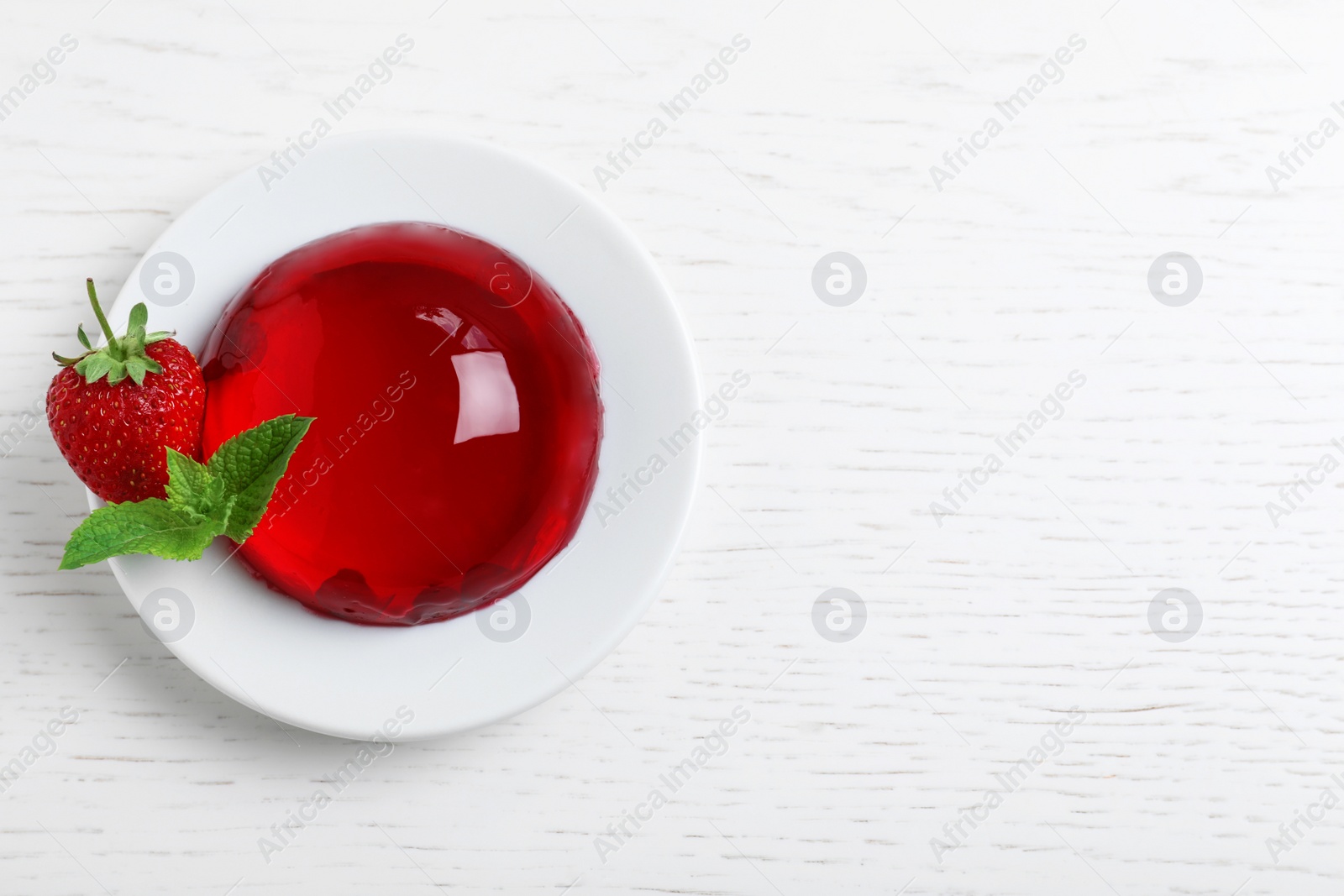 Photo of Delicious fresh red jelly with berries and mint on white wooden table, top view. Space for text