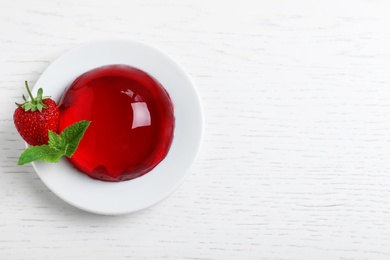 Delicious fresh red jelly with berries and mint on white wooden table, top view. Space for text