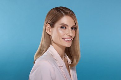 Image of Portrait of stylish attractive woman with blonde hair smiling on light blue background
