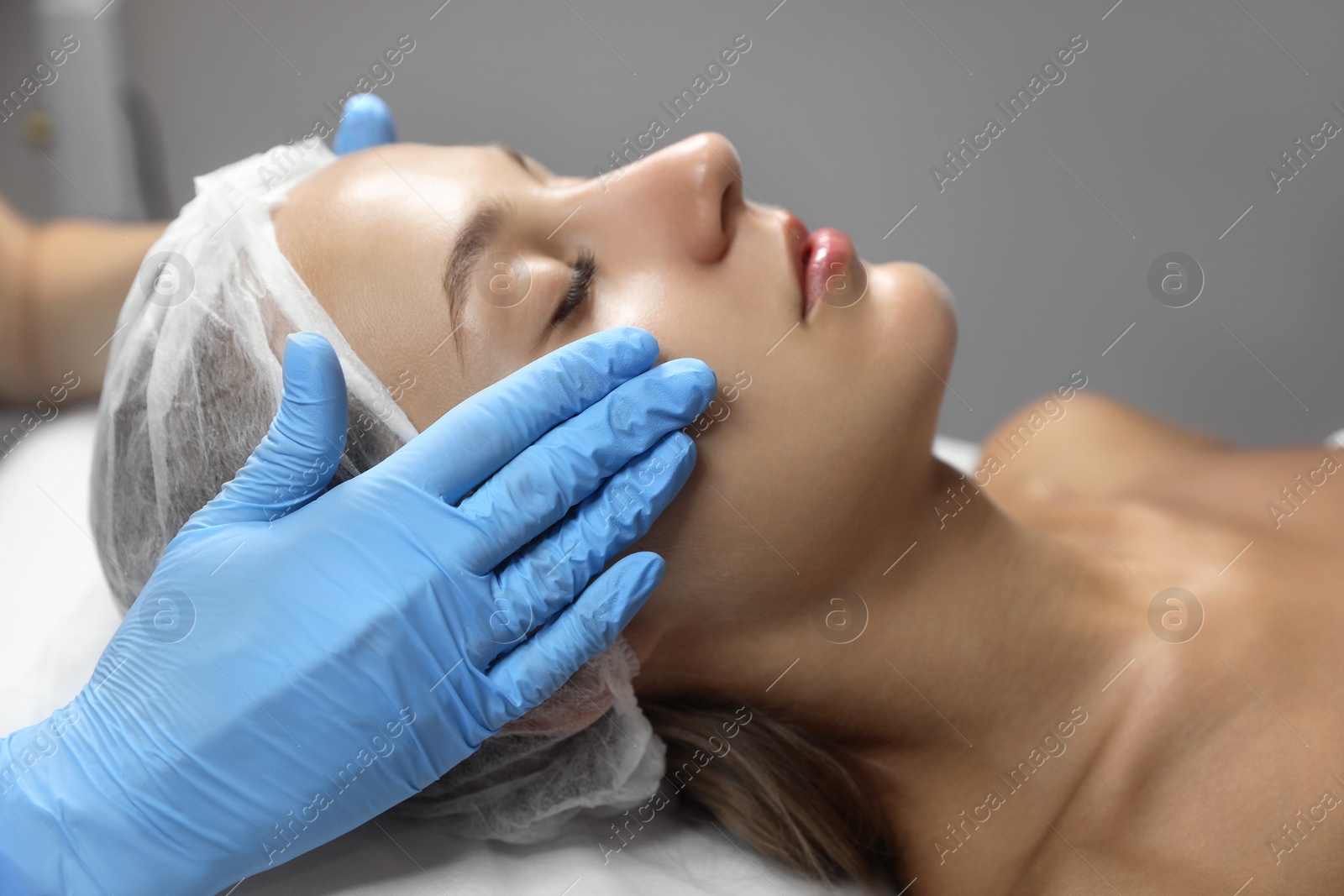 Photo of Young woman receiving facial massage in salon