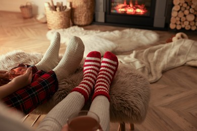 Couple in knitted socks near fireplace at home, closeup of legs