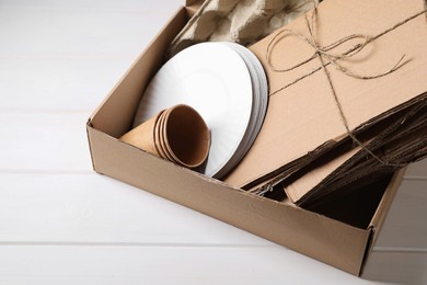 Box of waste paper on white wooden table, above view