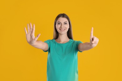 Photo of Woman showing number six with her hands on yellow background