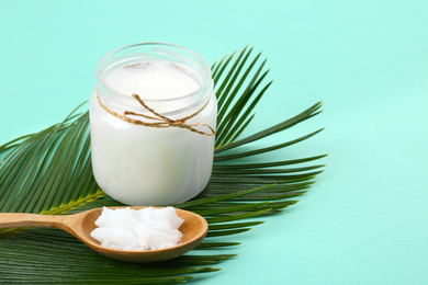 Photo of Organic coconut oil and palm branch on turquoise background. Healthy cooking