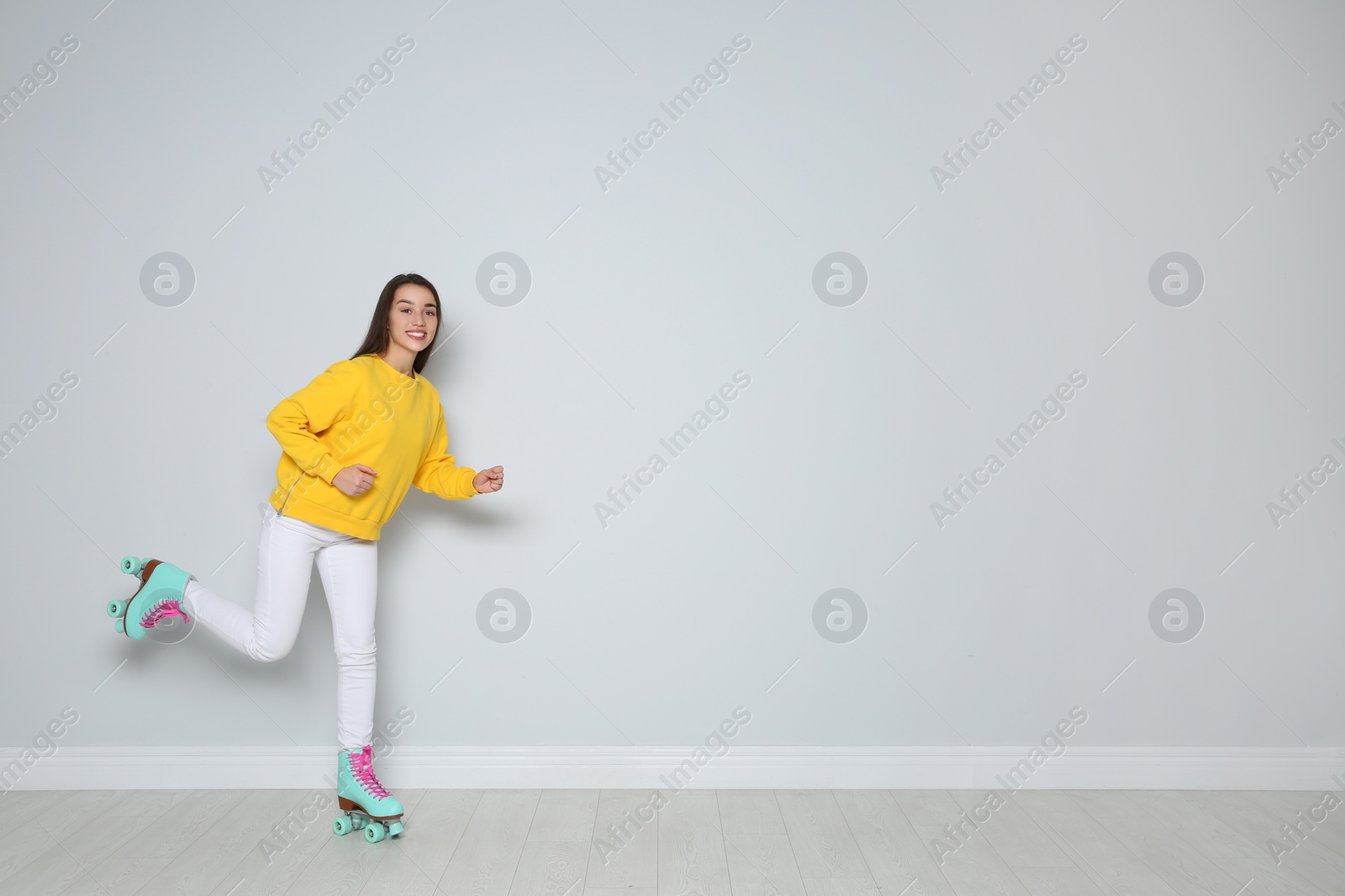 Photo of Young woman with roller skates near color wall. Space for text