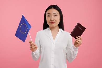 Immigration to European Union. Woman with passport and flag on pink background