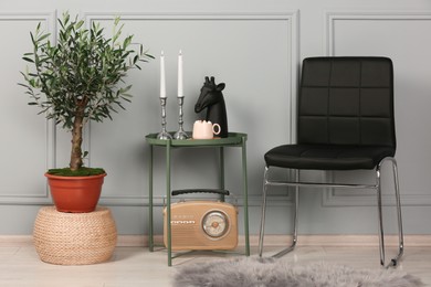 Photo of Stylish room interior with modern furniture, fancy decor elements and beautiful young potted olive tree