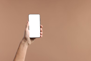 Photo of Man holding smartphone with blank screen on beige background, closeup. Mockup for design