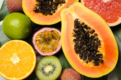 Fresh ripe papaya and other fruits on green leaf, top view