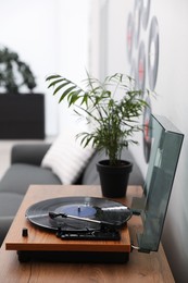 Photo of Stylish turntable with vinyl disc in living room