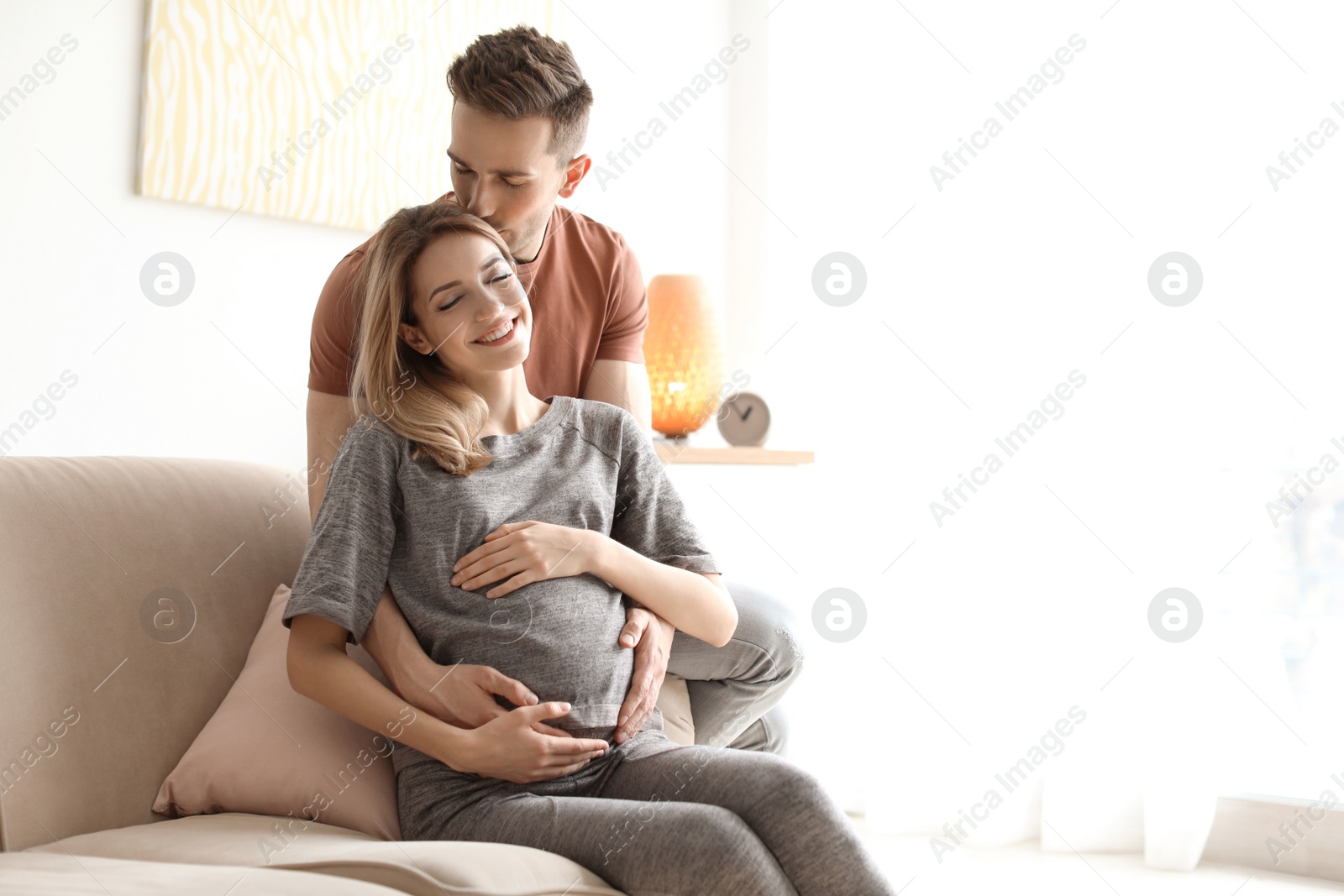 Photo of Young pregnant woman with her husband at home