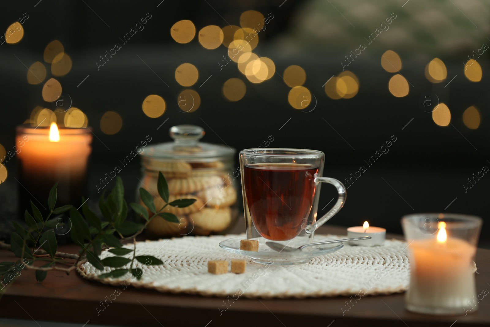 Photo of Tea, cookies and decorative elements on wooden table against blurred lights indoors