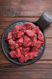 Photo of Pieces of raw beef meat on wooden table, top view