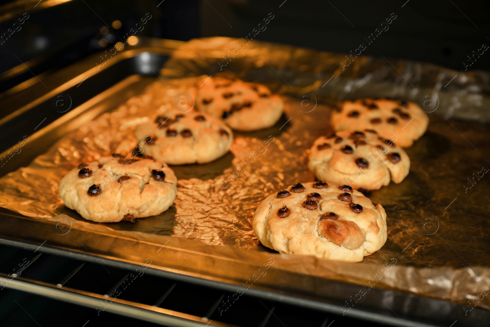 Photo of Baking delicious chocolate chip cookies in oven, closeup