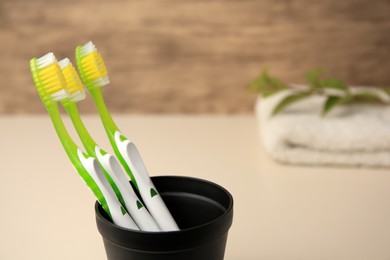 Photo of Toothbrushes in holder on blurred background, closeup. Space for text