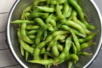 Sieve with green edamame beans in pods on table, top view