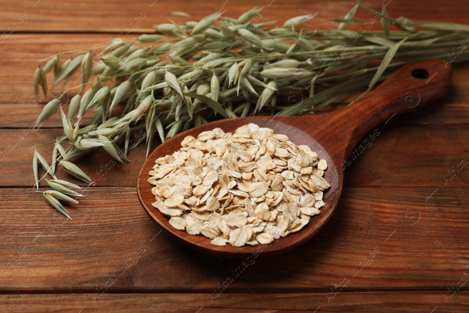 Photo of Spoon with oatmeal and floret branches on wooden table