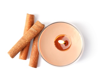 Color wax candle in glass holder and cinnamon sticks isolated on white, top view