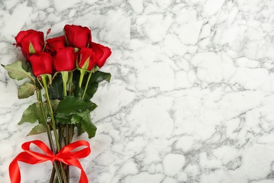 Beautiful red roses and space for text on white marble background, top view. Valentine's Day celebration