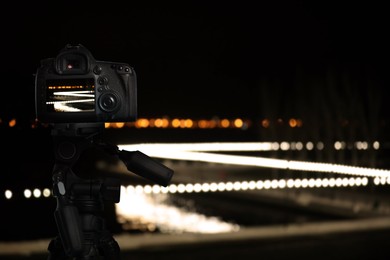 Image of Taking photo of with camera mounted on tripod. Blurred view of city lights at night, bokeh effect