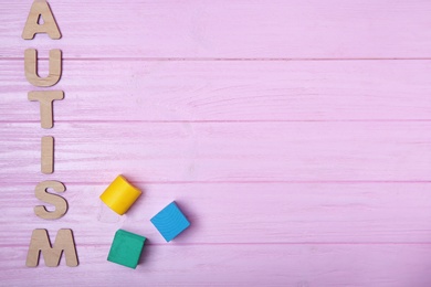 Photo of Word AUTISM and cubes on color background, top view