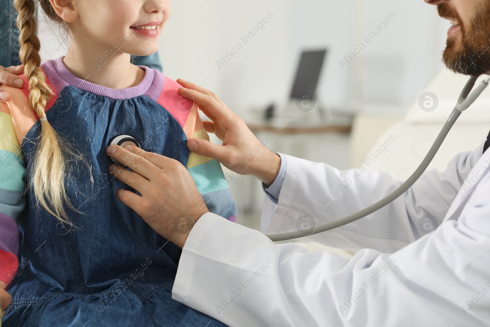 Photo of Pediatrician examining little patient with stethoscope in clinic, closeup