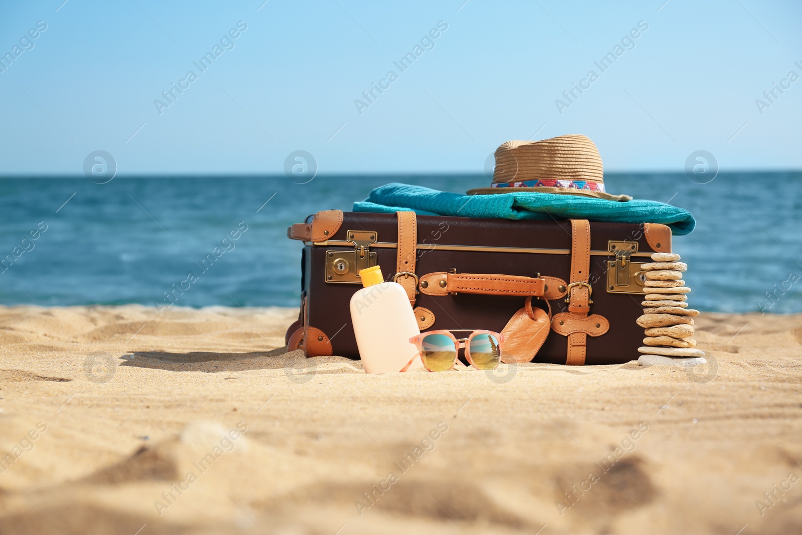 Photo of Suitcase and beach accessories on sand near sea. Space for text