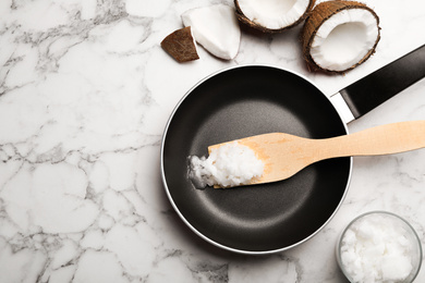 Flat lay composition with coconut oil and frying pan on white marble table, space for text. Healthy cooking