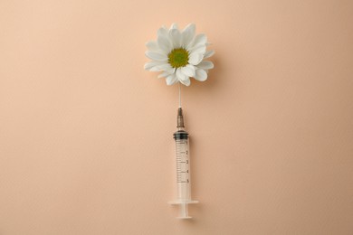 Photo of Medical syringe and beautiful chrysanthemum flower on beige background, top view
