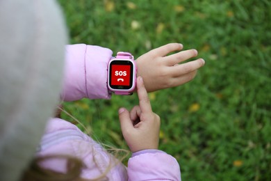 Image of Little girl using SOS function on smartwatch outdoors, closeup