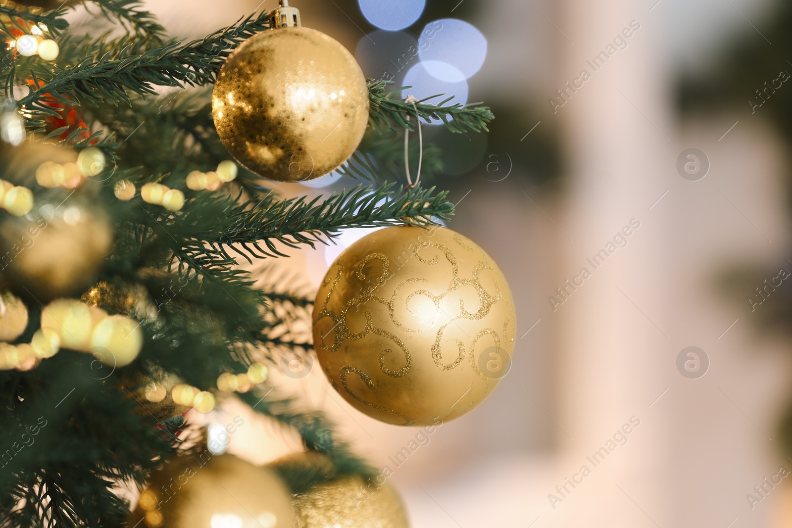 Photo of Christmas tree decorated with golden festive balls on light background, closeup. Space for text