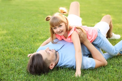 Photo of Father with his cute child on green grass in park. Happy family