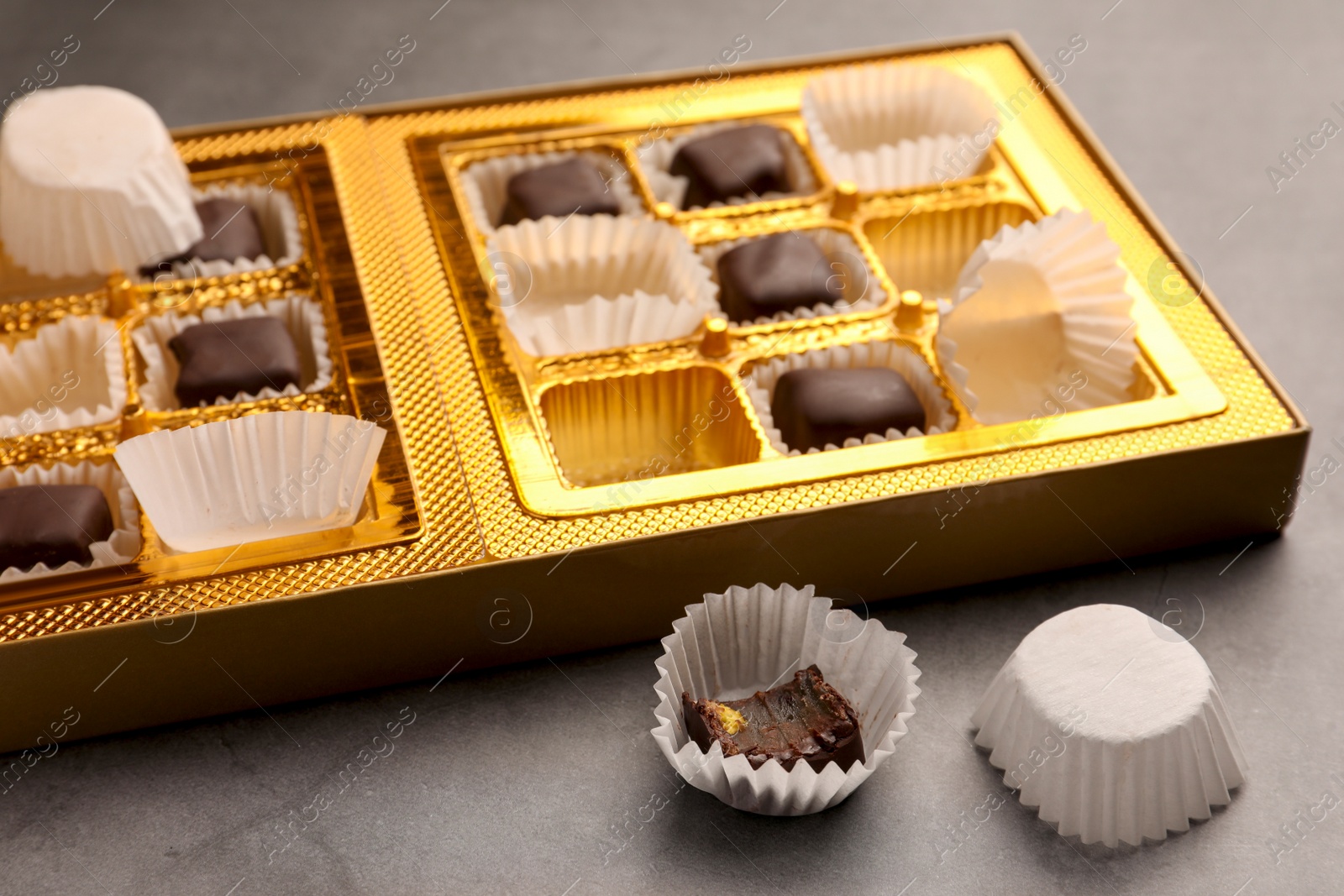 Photo of Partially empty box of chocolate candies on grey table