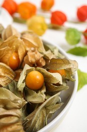 Photo of Ripe physalis fruits with dry husk on white table, closeup