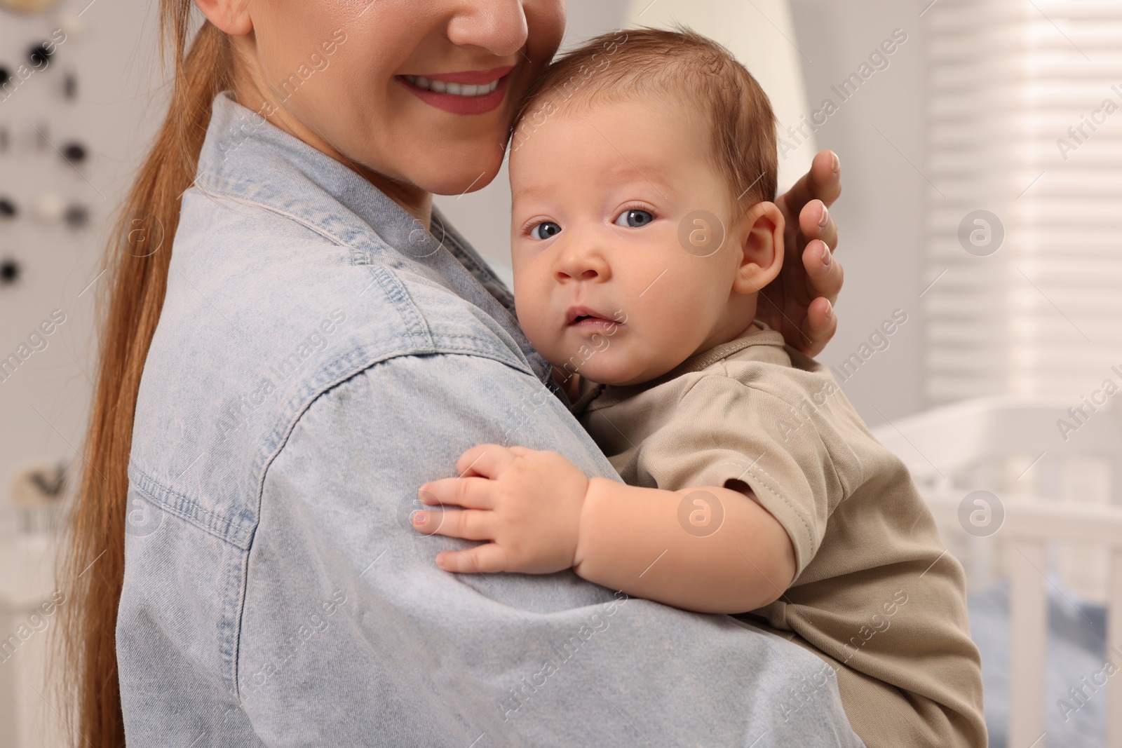 Photo of Mother holding her cute newborn baby at home, closeup