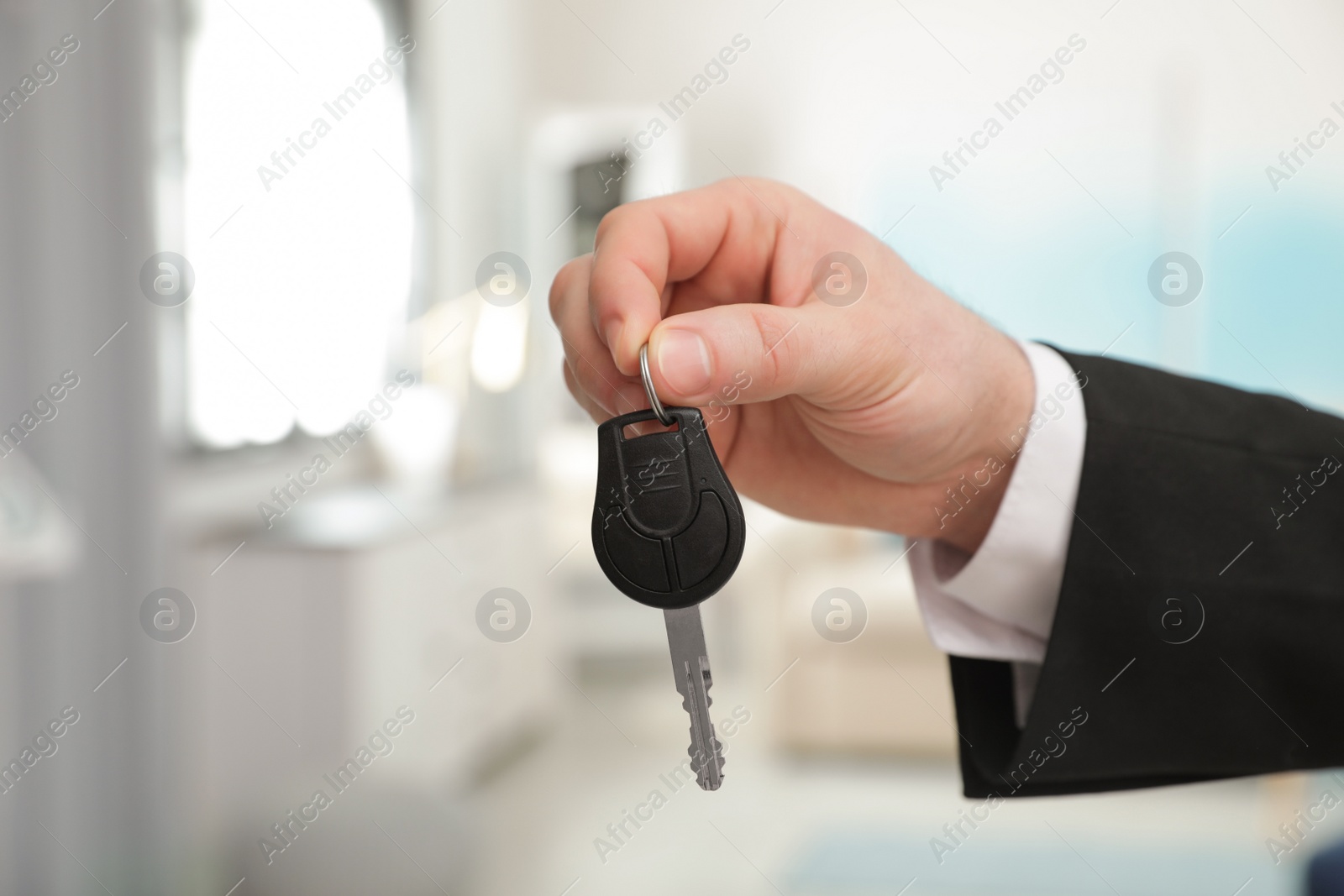 Photo of Man holding car key indoors, closeup. Space for text