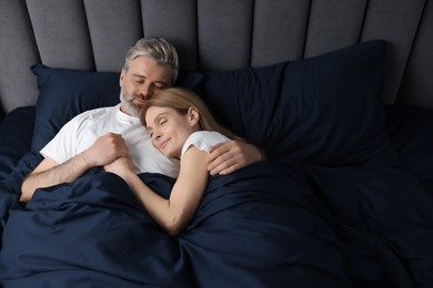 Photo of Lovely mature couple sleeping together in bed at home, above view