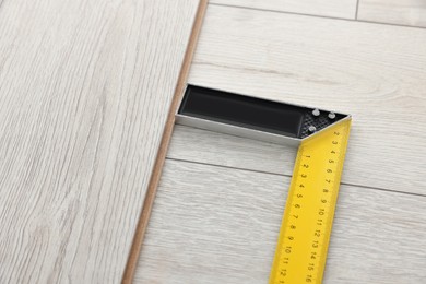 Photo of Ruler, pencil and parquet plank on laminated flooring, closeup