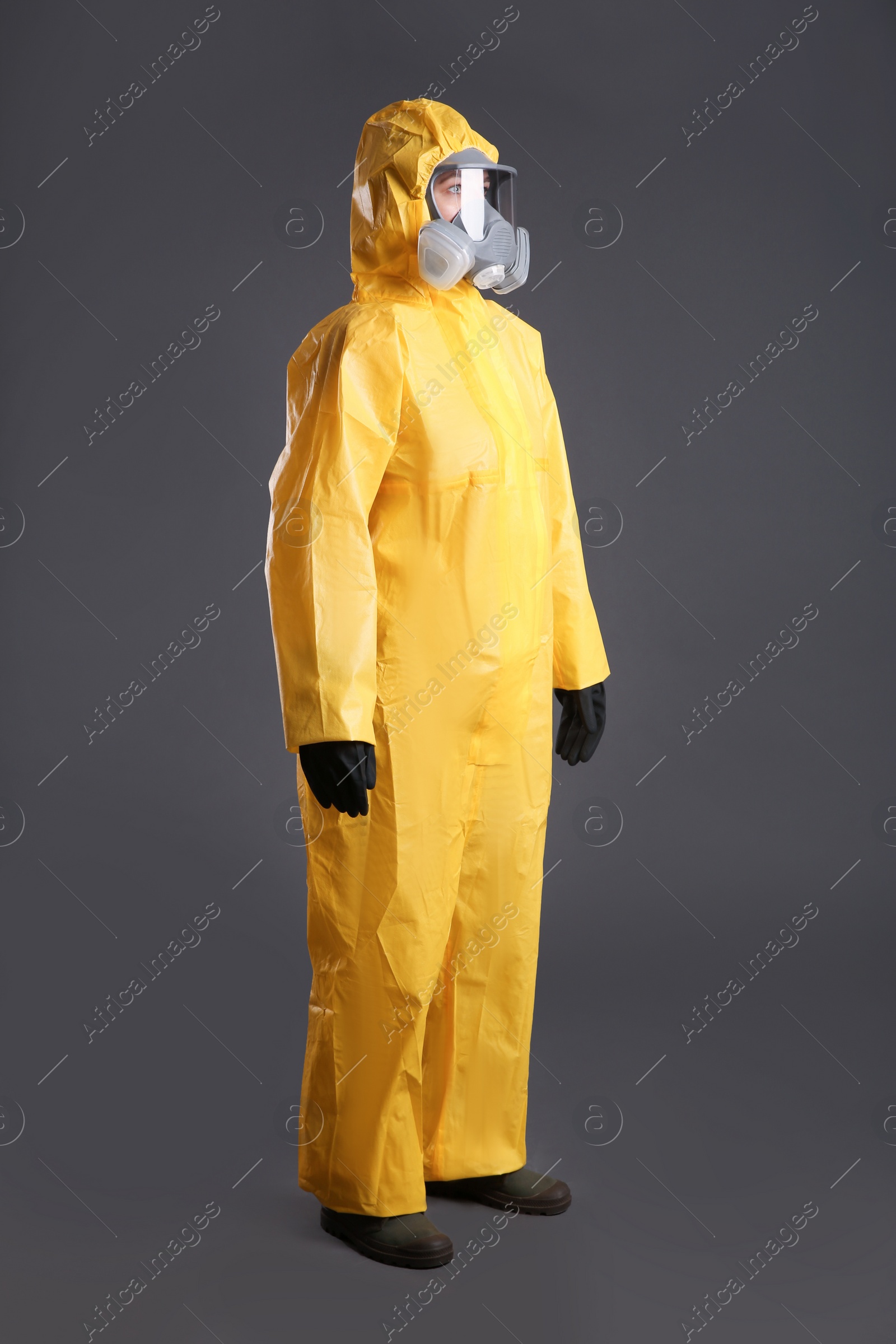 Photo of Woman wearing chemical protective suit on grey background. Virus research