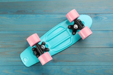 Photo of Bright skateboard on turquoise wooden background, top view. Sport equipment