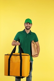 Photo of Young courier with thermo bag on color background. Food delivery service