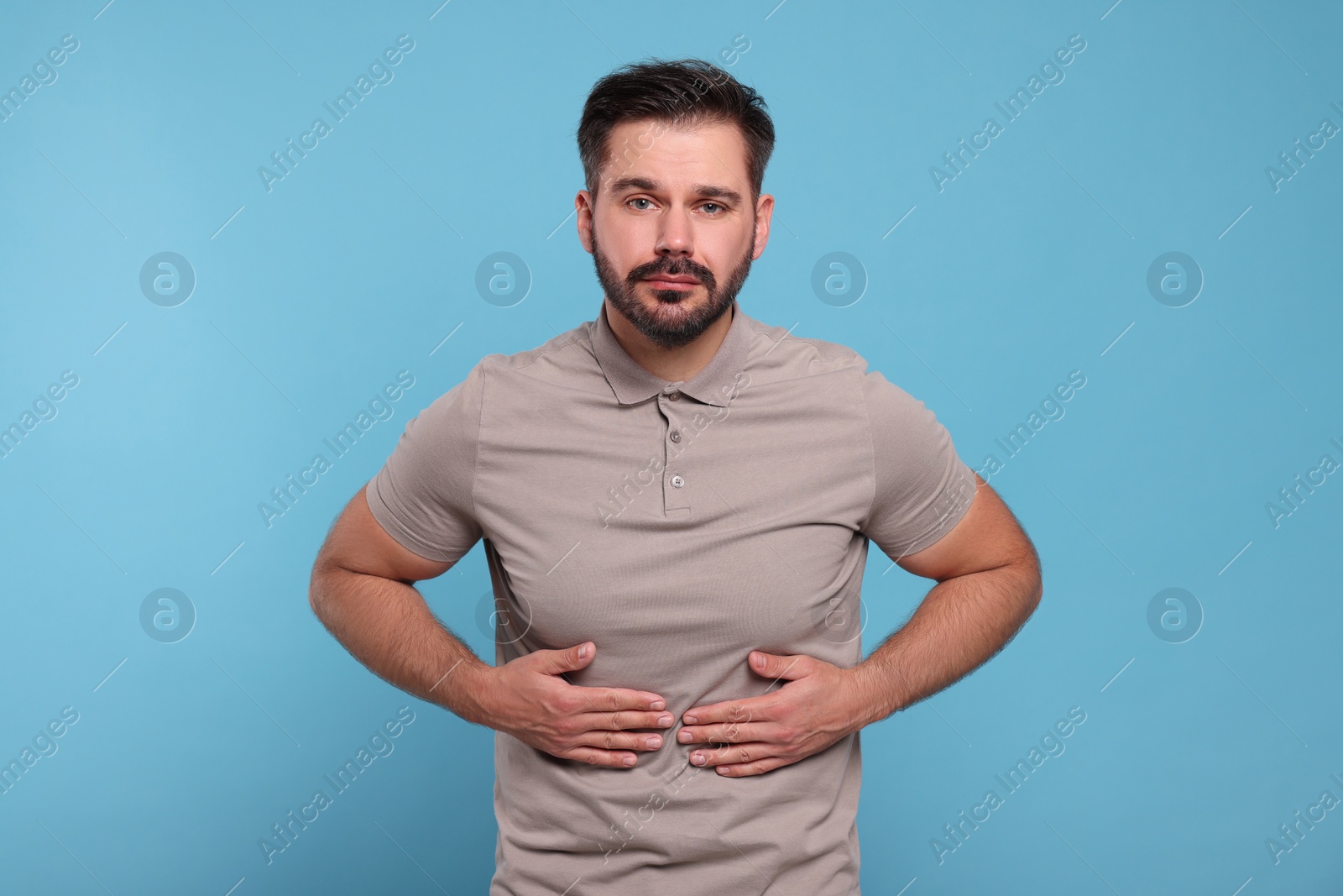 Photo of Man suffering from stomach pain on light blue background