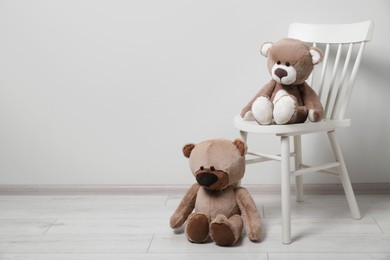 Cute teddy bears and chair indoors, space for text