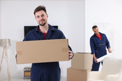 Male mover with cardboard box in house, space for text