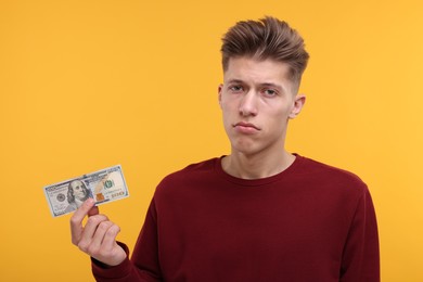 Photo of Upset man with dollar banknote on yellow background