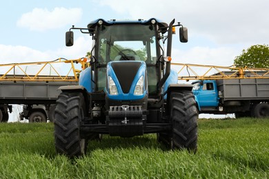 Modern tractor and truck in field on sunny day. Agricultural industry